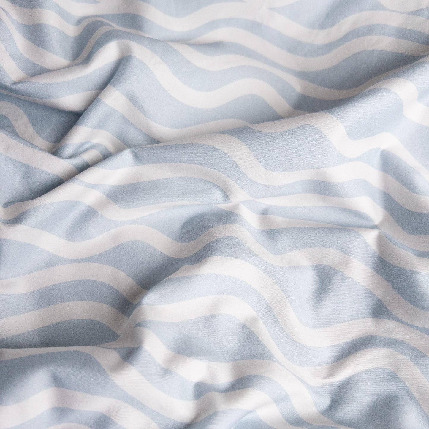 Close-up of bright waves organic cotton waterproof fabric used in Little Human Linens fitted sheet, showing soft textured weave