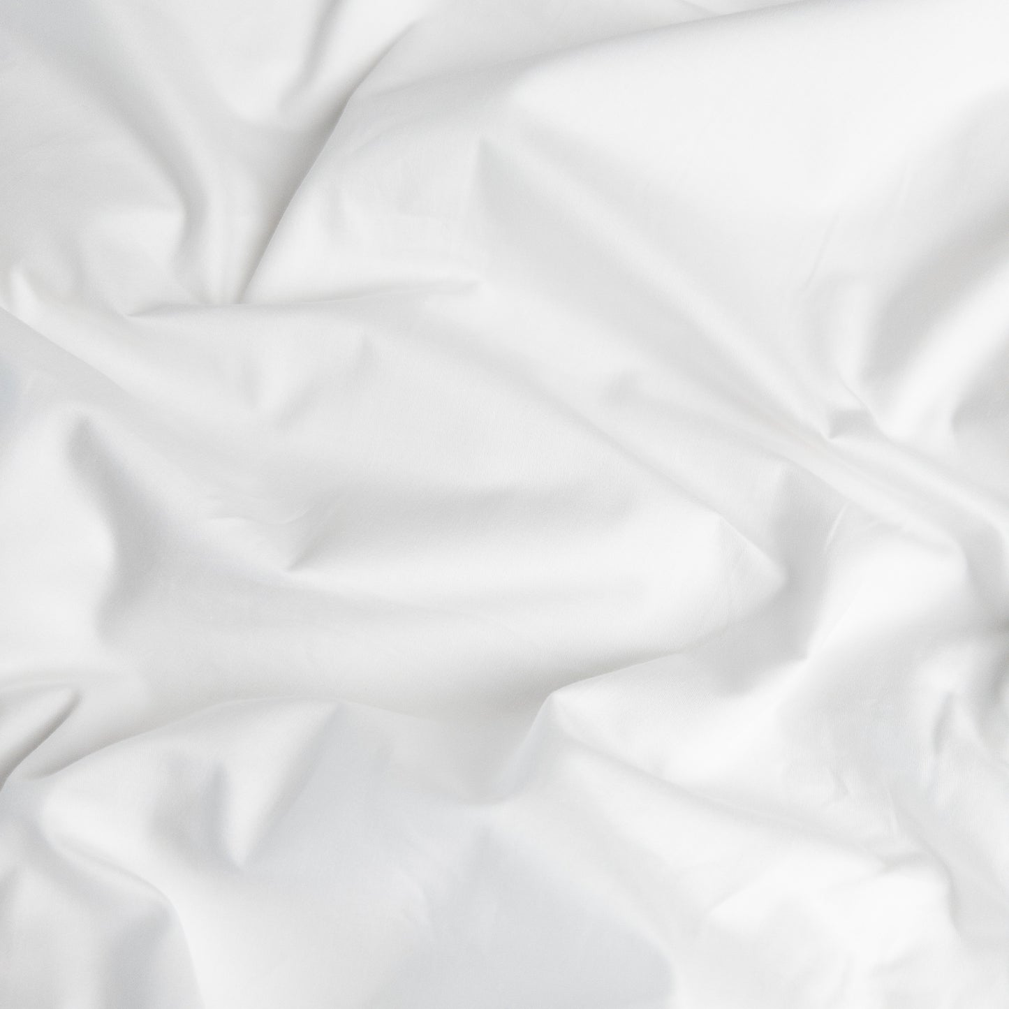 Close-up of brilliant white organic cotton waterproof fabric used in Little Human Linens fitted sheet, showing soft textured weave