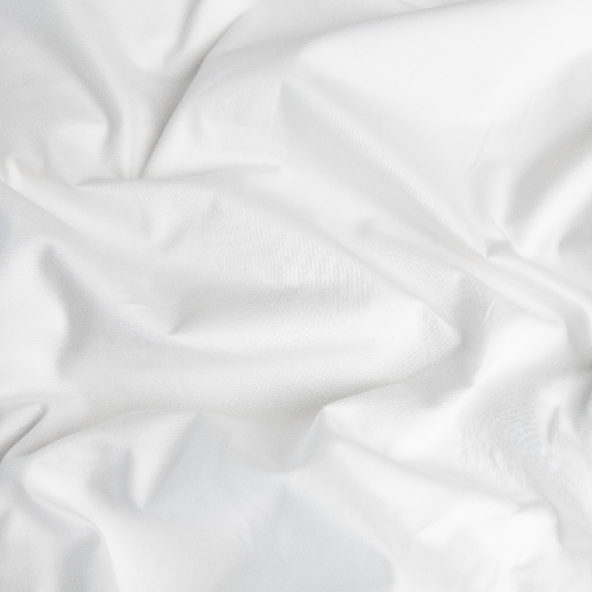 Close-up of brilliant white organic cotton waterproof fabric used in Little Human Linens fitted sheet, showing soft textured weave