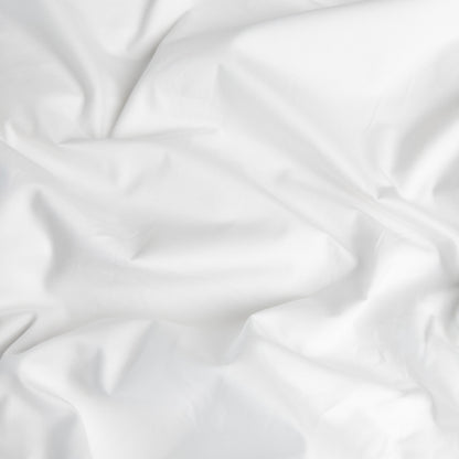 Close-up of brilliant white organic cotton waterproof fabric used in Little Human Linens fitted sheet, showing soft textured weave