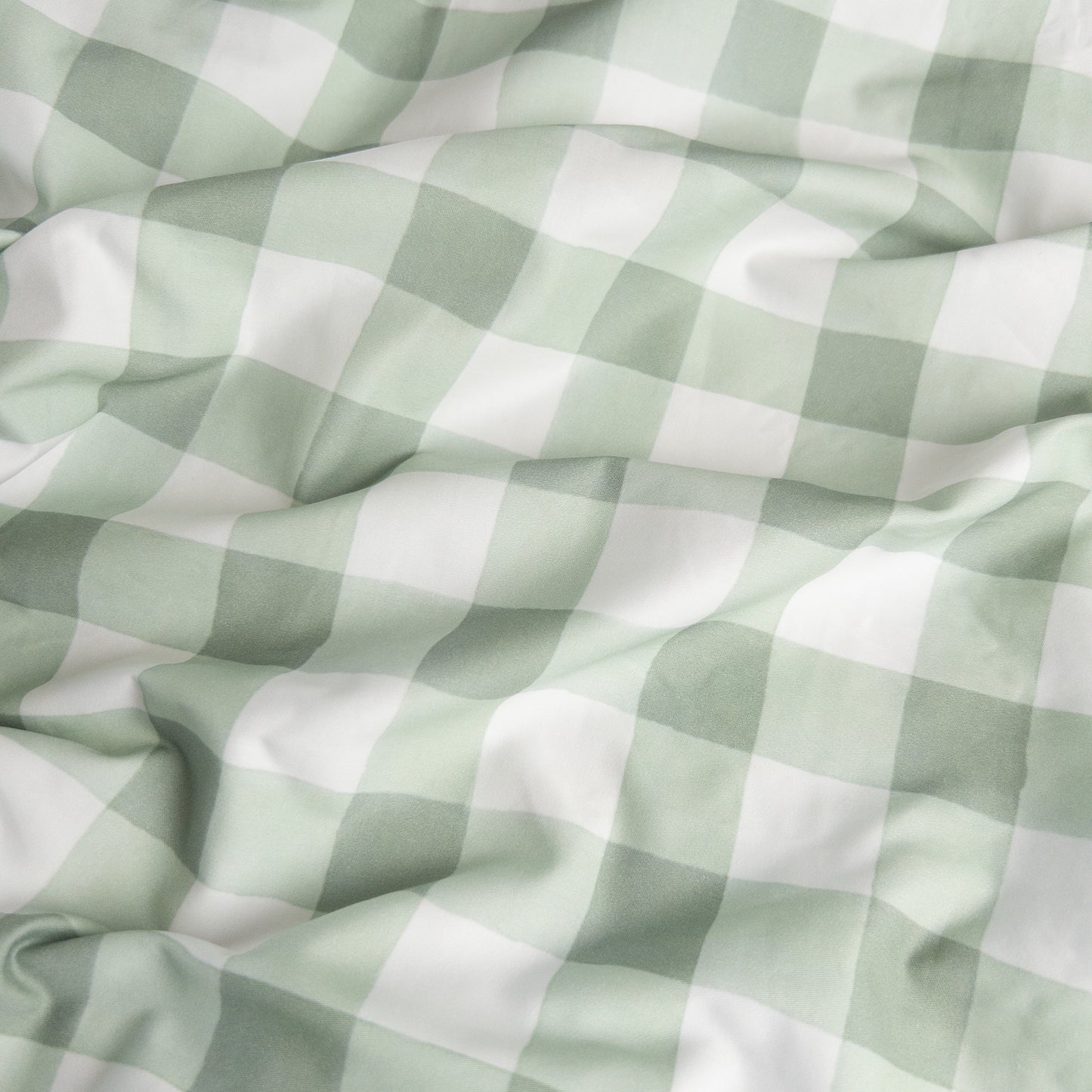 Close-up of green gingham organic cotton waterproof fabric used in Little Human Linens fitted sheet, showing soft textured weave