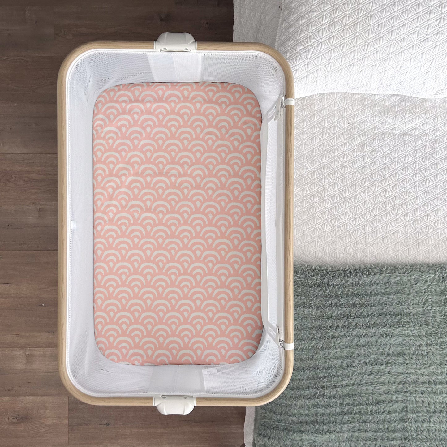 Little Human Linens Peach Rainbows waterproof fitted sheet shown from above, fitted snugly on a co-sleeper mattress