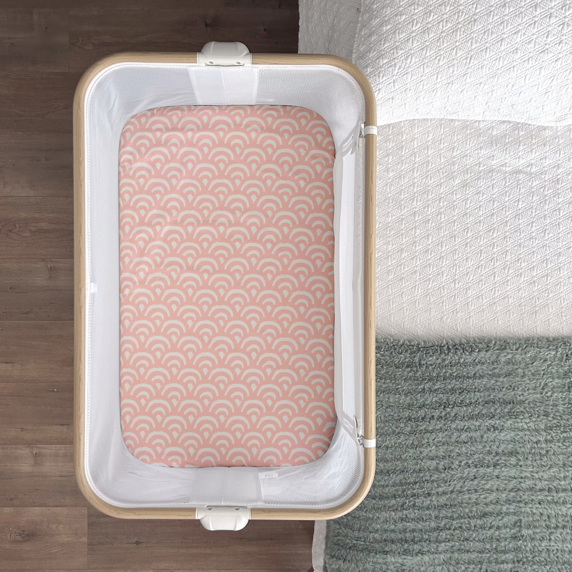 Little Human Linens Peach Rainbows waterproof fitted sheet shown from above, fitted snugly on a co-sleeper mattress