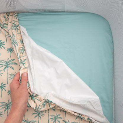 Little Human Linens Green Palms co-sleeper fitted sheet pulled back to reveal the waterproof layer underneath