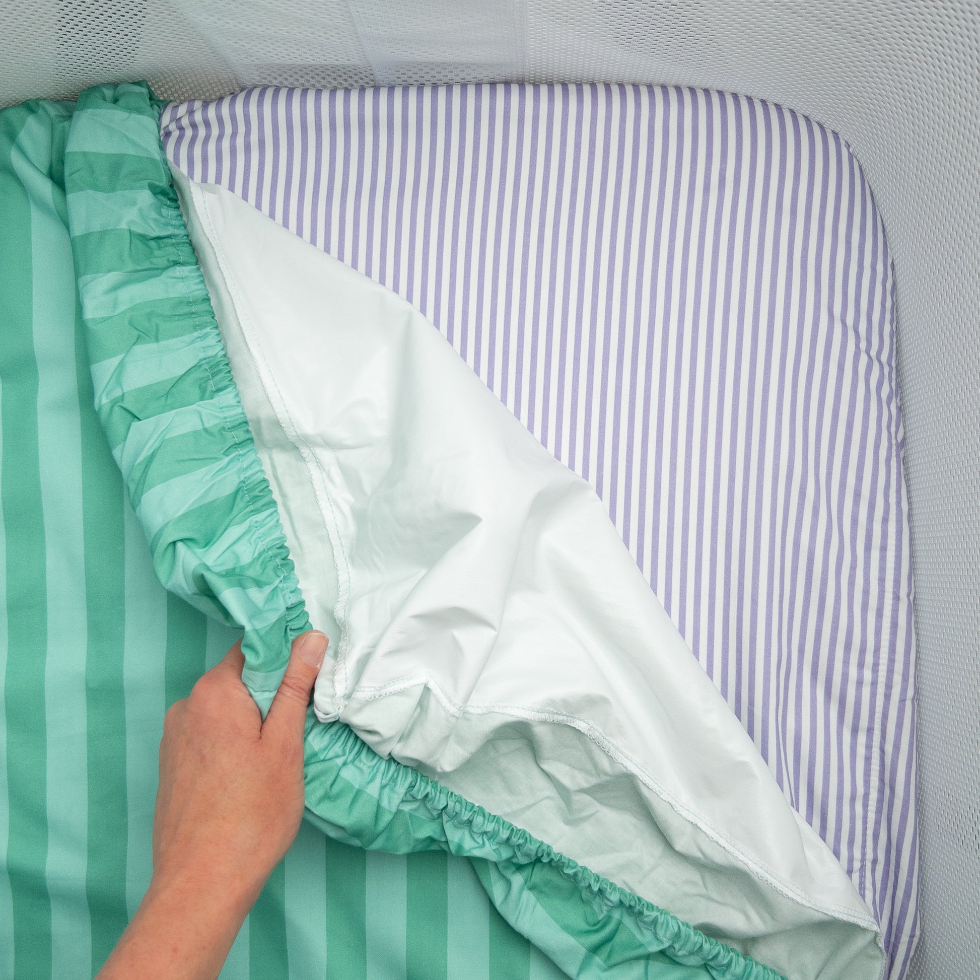 Little Human Linens Mint Candy co-sleeper fitted sheet pulled back to reveal the waterproof layer underneath