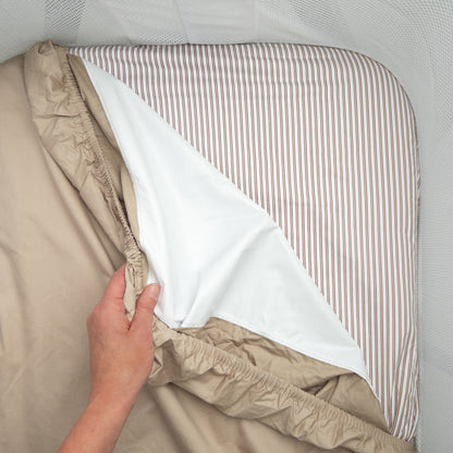 Little Human Linens Mocha Pinstripe co-sleeper fitted sheet pulled back to reveal the waterproof layer underneath