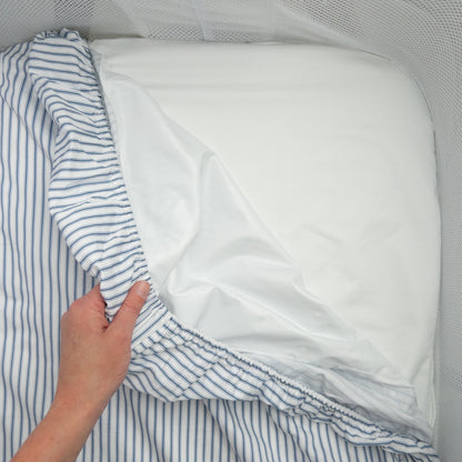 Little Human Linens Navy Ticking co-sleeper fitted sheet pulled back to reveal the waterproof layer underneath