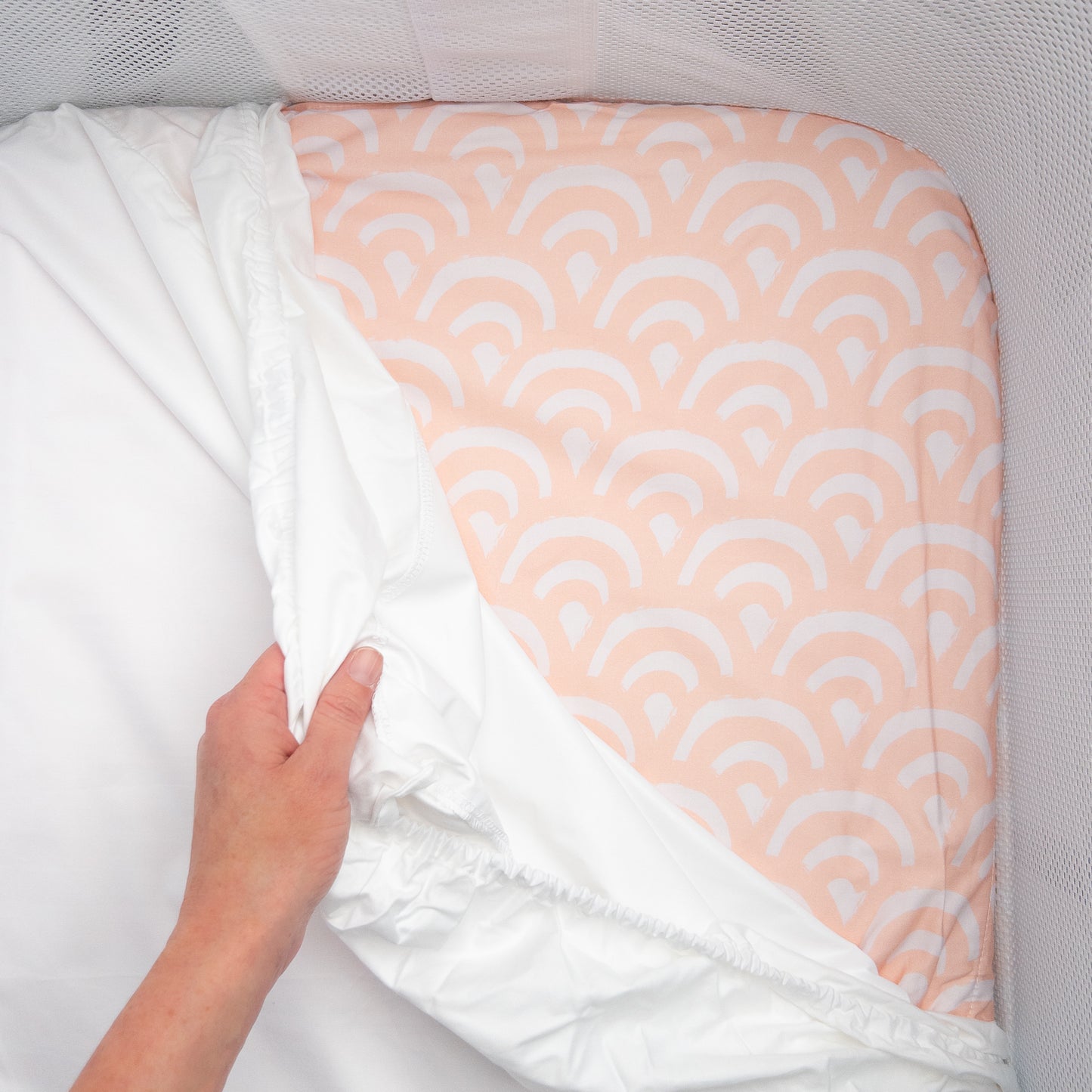 Little Human Linens Peach Rainbows co-sleeper fitted sheet pulled back to reveal the waterproof layer underneath