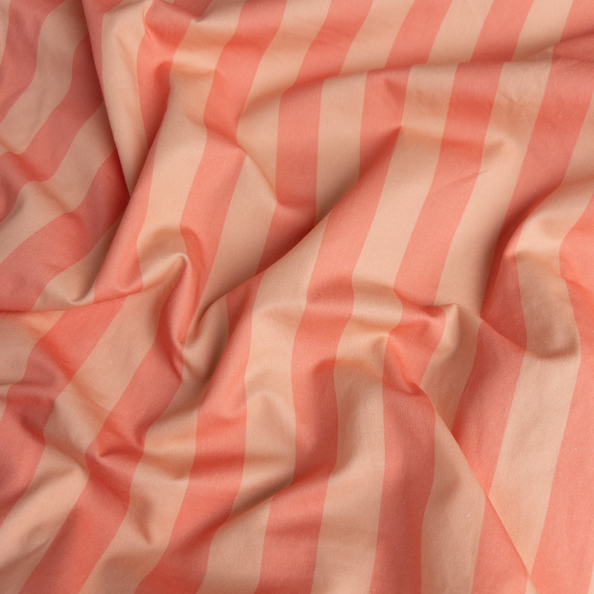 Close-up of peach candy organic cotton waterproof fabric used in Little Human Linens fitted sheet, showing soft textured weave
