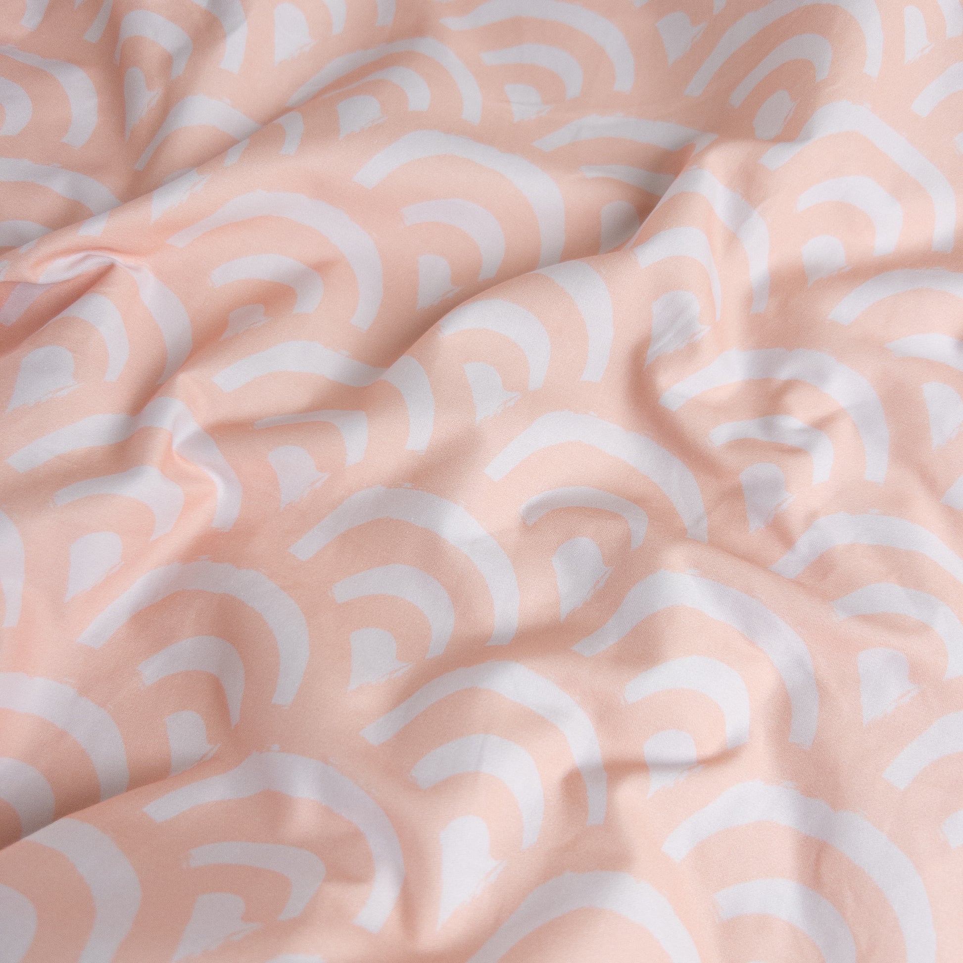 Close-up of peach rainbows gingham organic cotton waterproof fabric used in Little Human Linens fitted sheet, showing soft textured weave