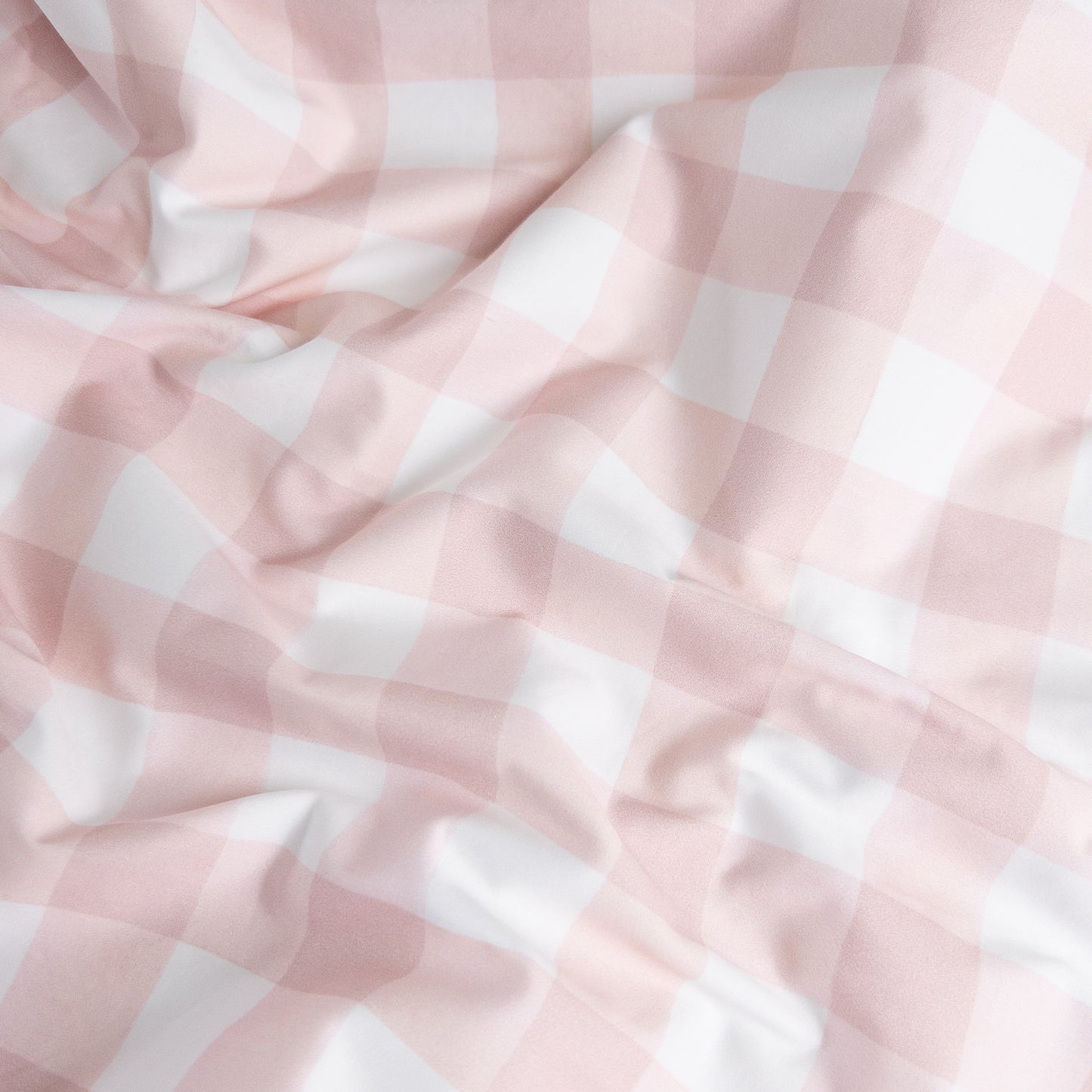 Close-up of pink gingham organic cotton waterproof fabric used in Little Human Linens fitted sheet, showing soft textured weave