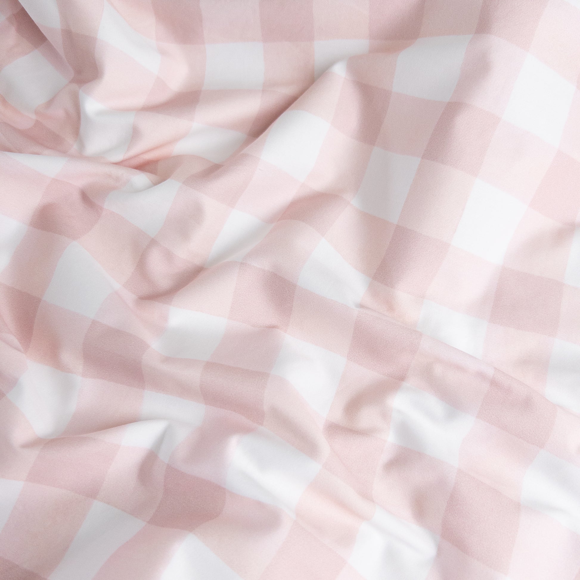Close-up of pink gingham organic cotton waterproof fabric used in Little Human Linens fitted sheet, showing soft textured weave