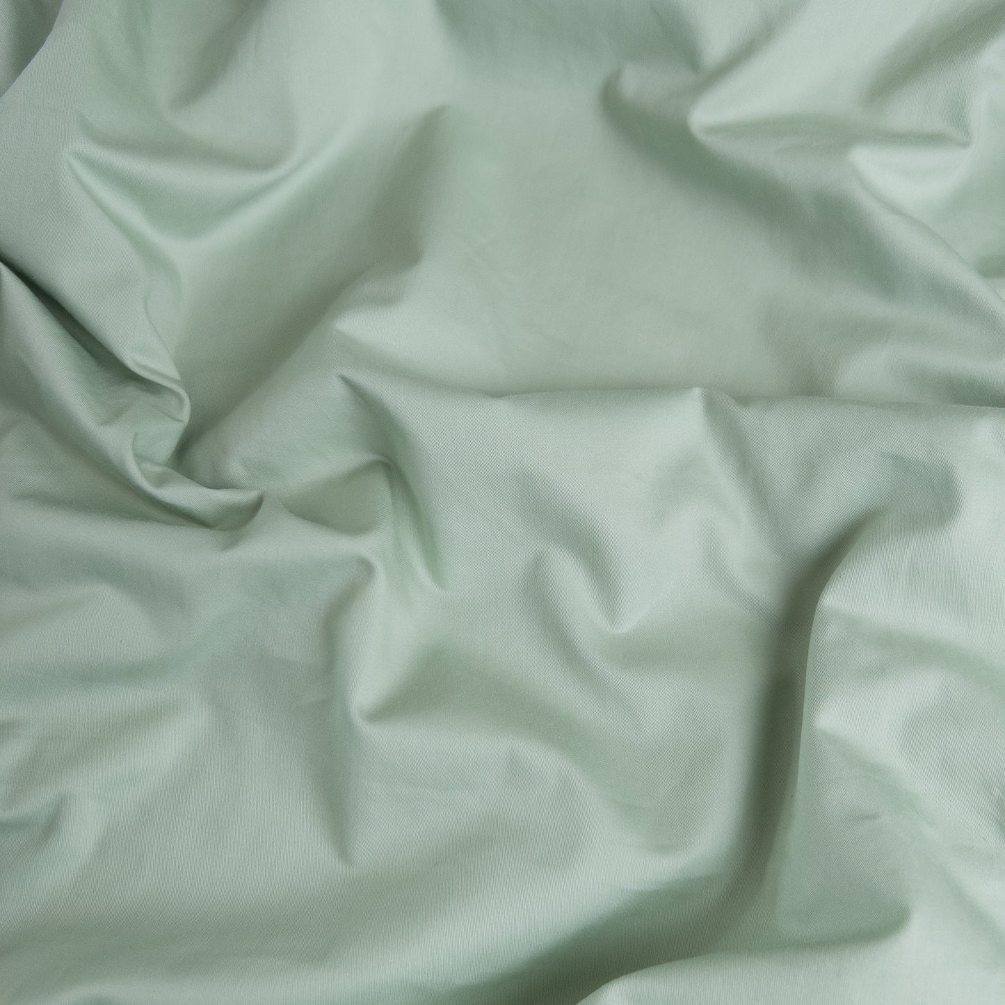 Close-up of sage organic cotton waterproof fabric used in Little Human Linens fitted sheet, showing soft textured weave