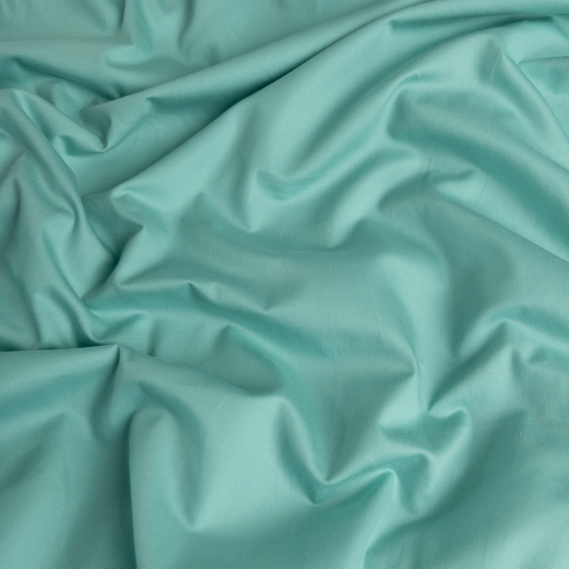 Close-up of teal organic cotton waterproof fabric used in Little Human Linens fitted sheet, showing soft textured weave